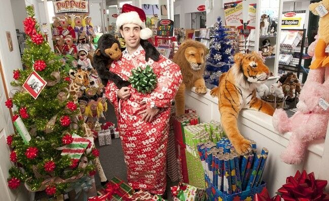 Man wrapped in paper with Santa hat in holiday store