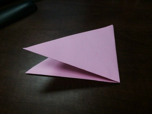 light pink paper folded in half into smaller triangle