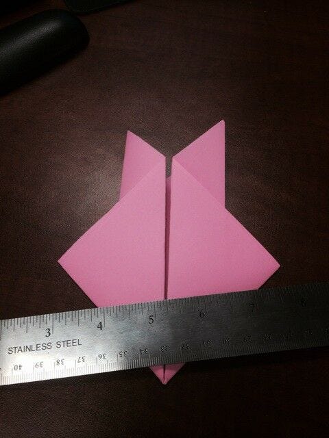 light pink paper folded and smoothed down with metallic silver steel ruler