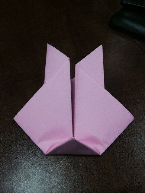 light pink origami bunny paper with bottom folded up slightly 