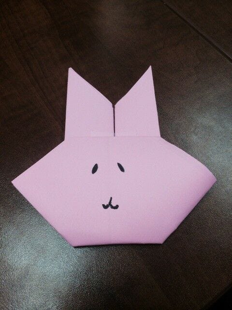 Completed light pink paper origami bunny with drawn on face