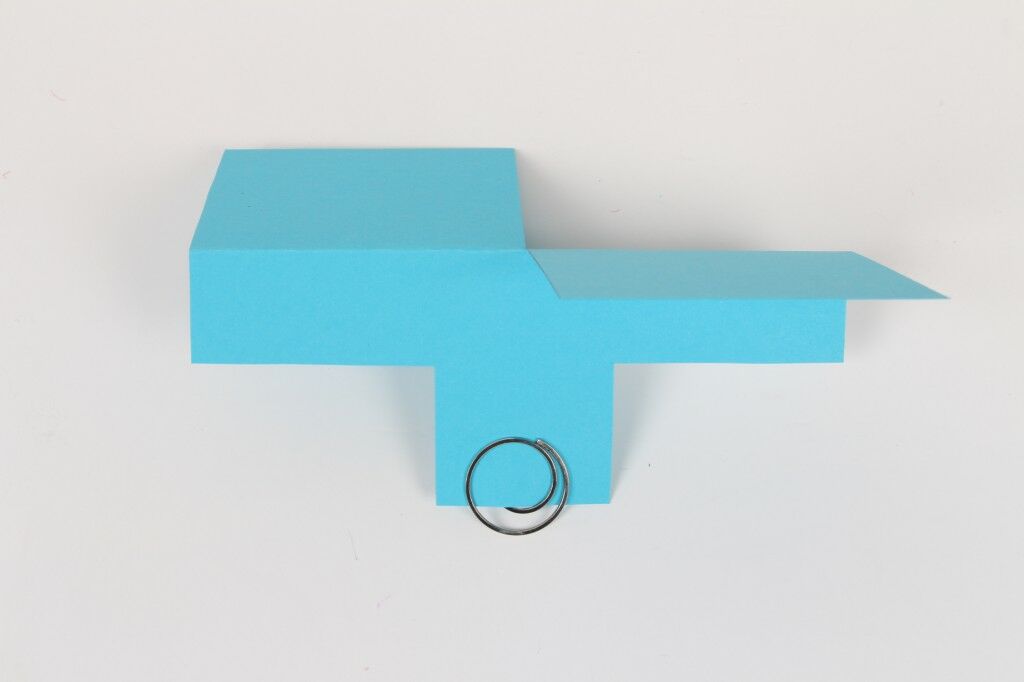 blue paper helicopter with circular paper clip clipped to bottom flap