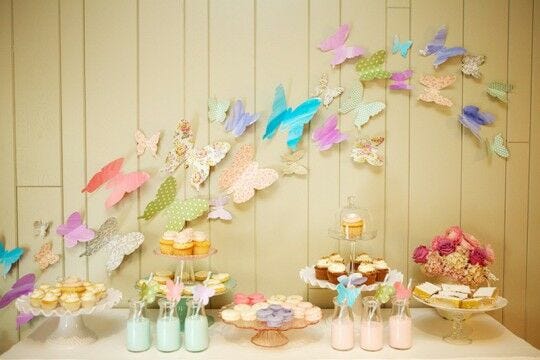 colorful butterflies flying on gold wall with food and beverages party table