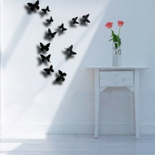 black butterflies on white wall with white side table and vase of flowers