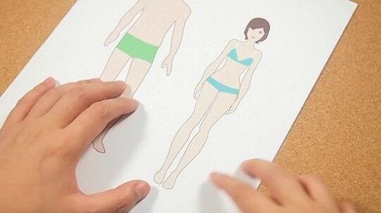 hands on white paper with male and female paper doll templates