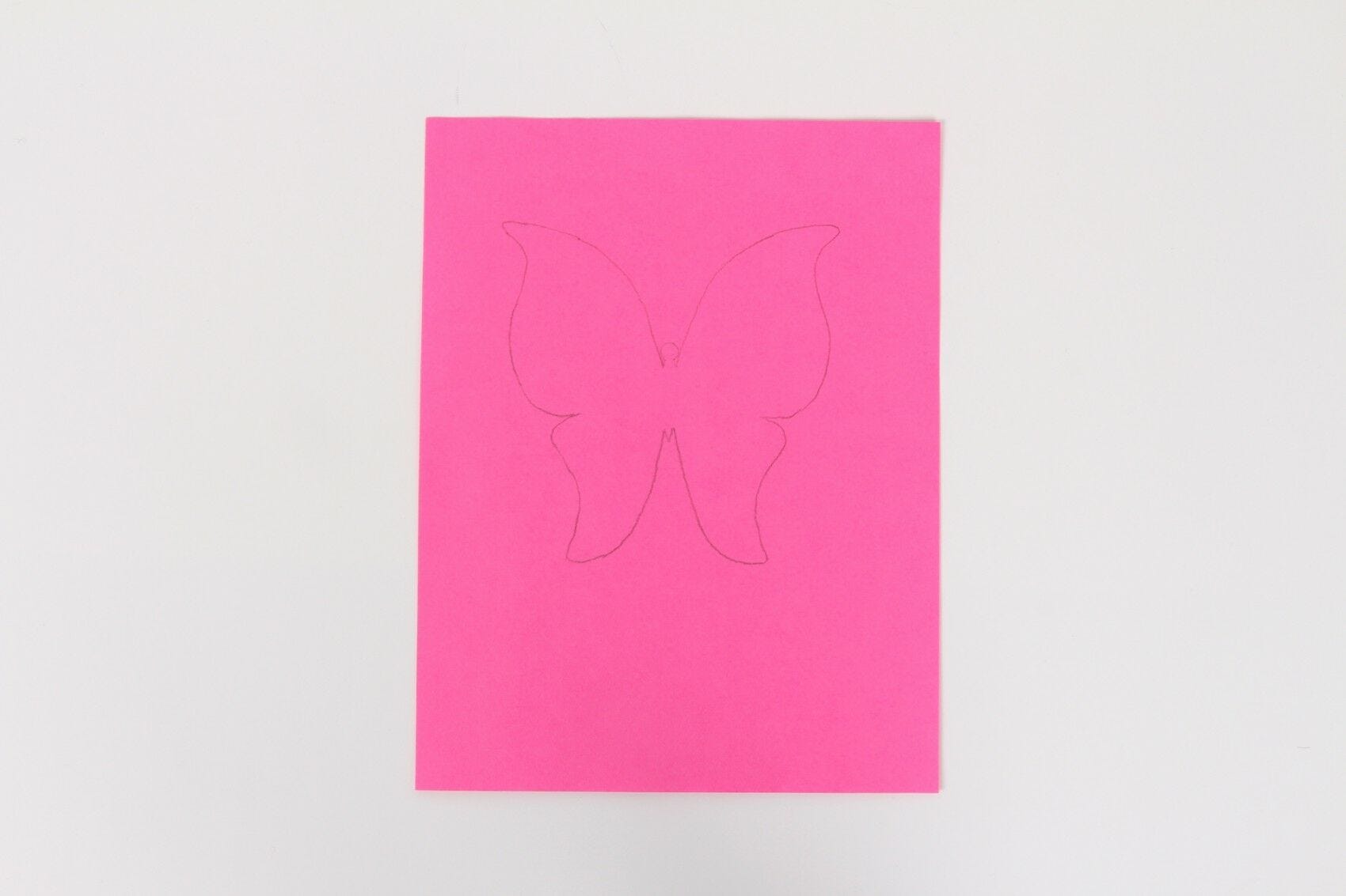pink paper with butterfly shape traced in pencil