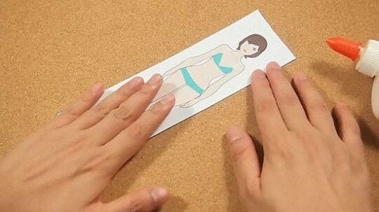 paper doll woman hands gluing female template to white cardstock