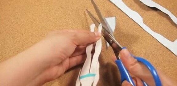 hands cutting out female doll with scissors