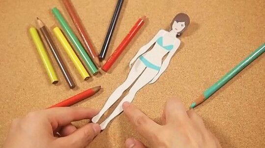 paper woman surrounded by colored pencils