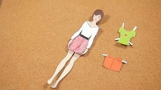 completed female paper doll with outfits laying on desk