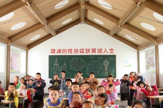 children in white and brown classroom with paper tubes in roof