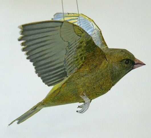 yellow and blue paper bird in flight suspended by string