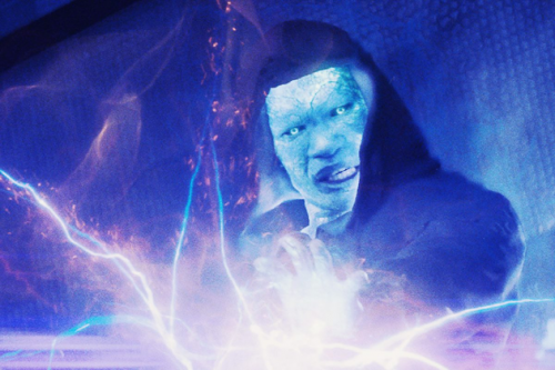 blue electro in hood with hand outstretched toward white electricity