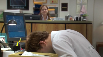 man at desk with his face planted to desk in the office