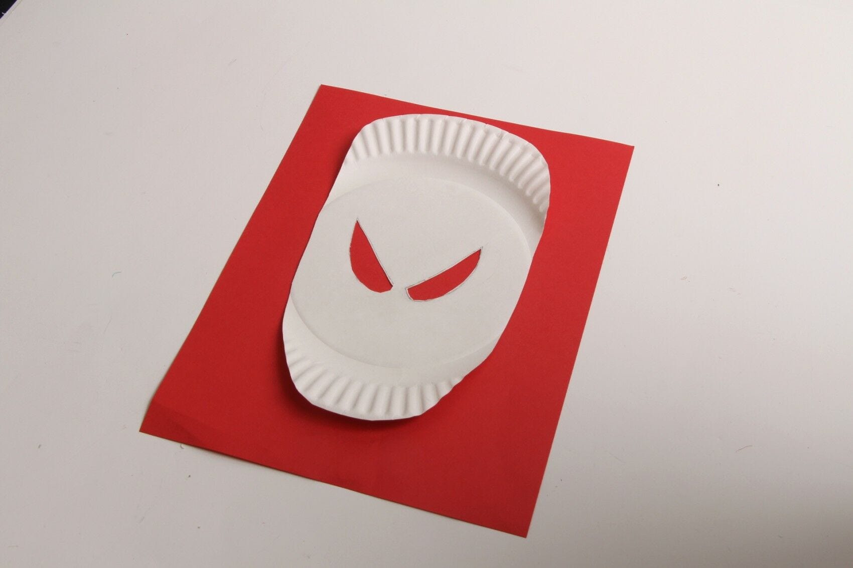 white paper plate spiderman mask glued to red paper