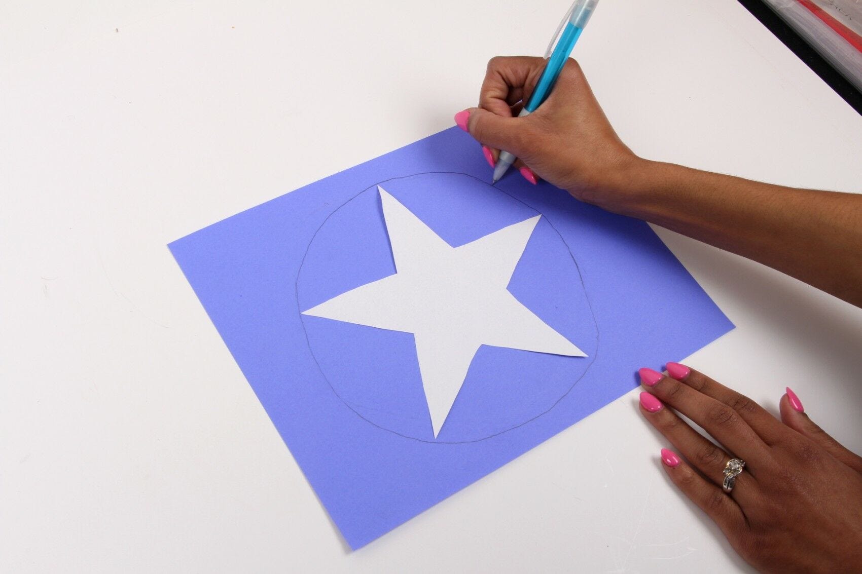 white star on blue paper, hands drawing circle around it