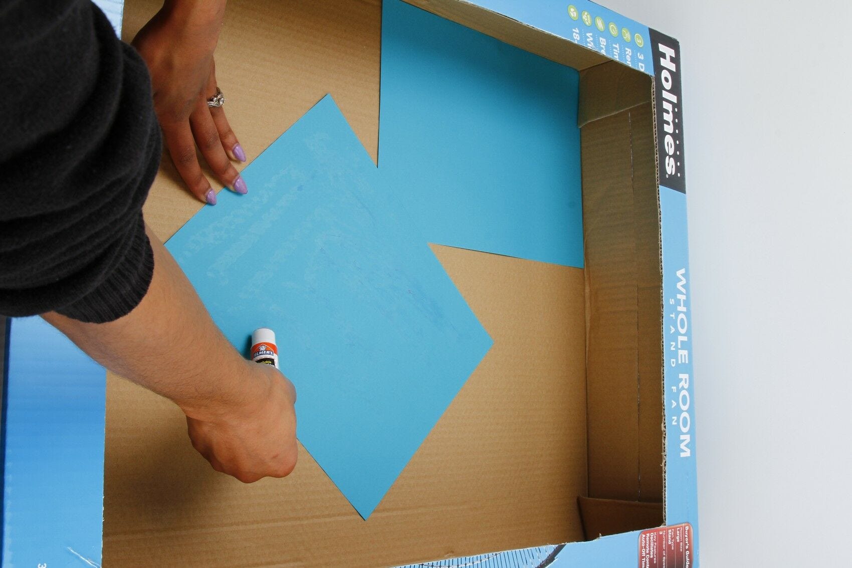 Open box, gluing paper to cardboard Putting blue paper in box