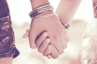 two women holding hands with bracelets