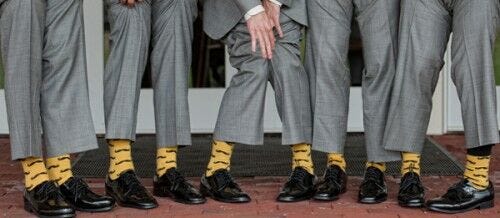row of gray dress pants with black dress shoes and yellow mustache socks
