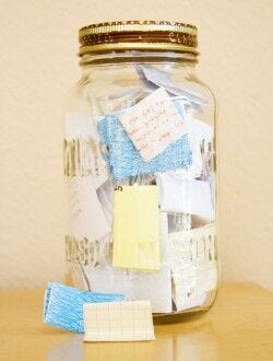 large glass jar filled with handwritten folded notes