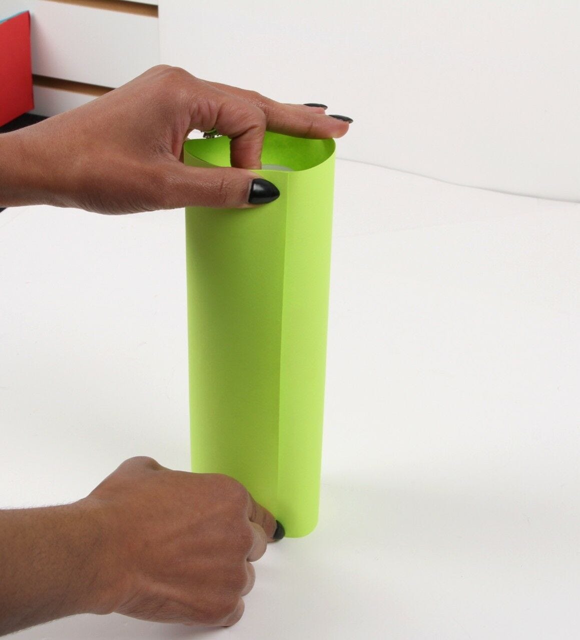 hands taping ends of lime green paper cylinder