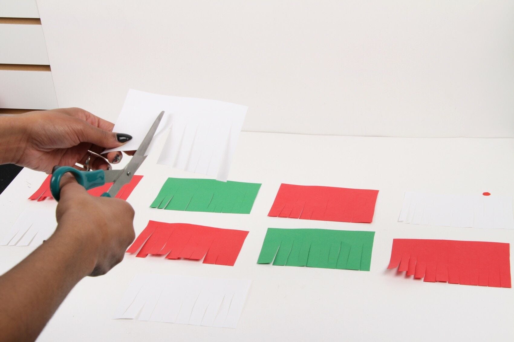 person cutting fringes on rectangular colored paper with scissors