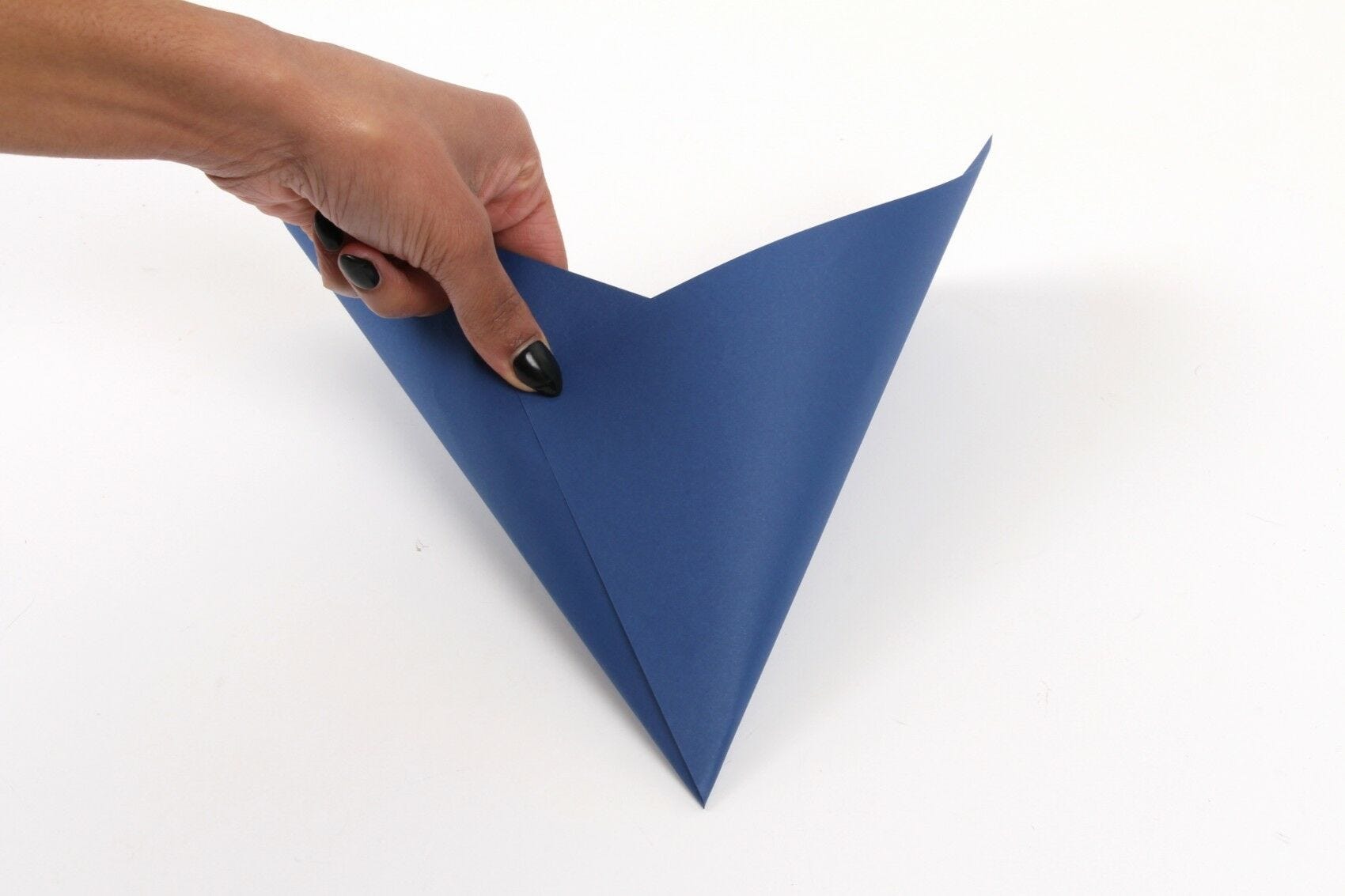 hands folding blue paper into pointed cone