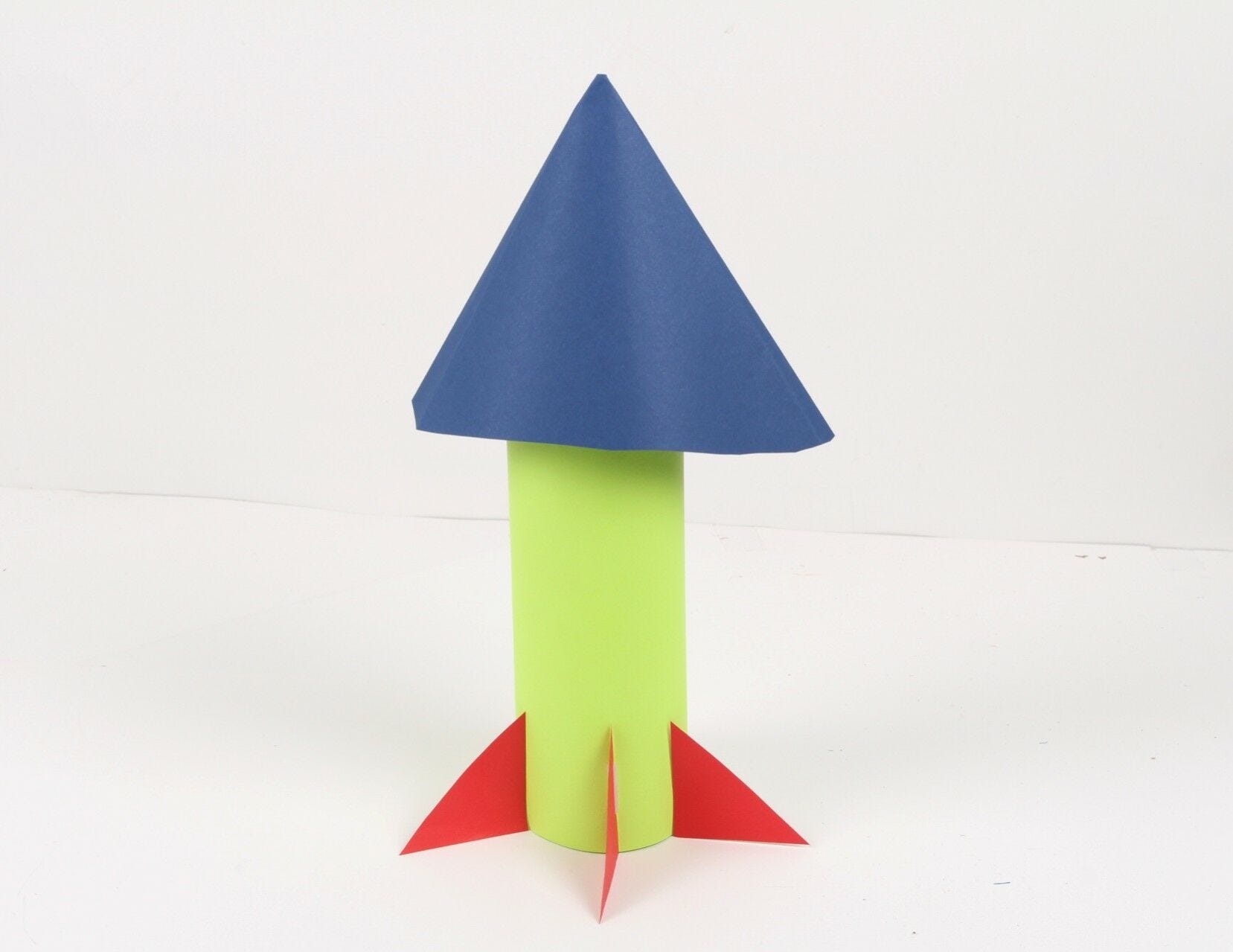 green blue and red paper water bottle spaceship standing on desk