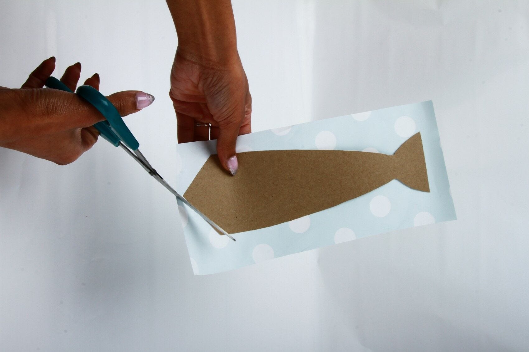 hands cutting cardstock around necktie