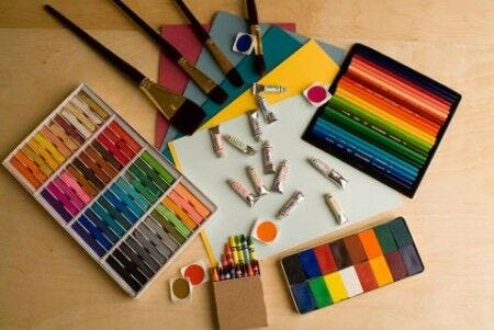 paint, oil pastels, colored pencils, crayons, colored paper, and other art materials spread out