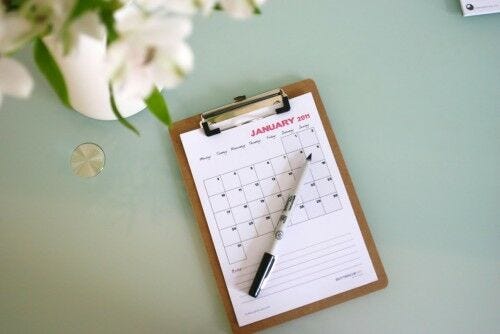 white paper calendar on clipboard with pen on blue desk