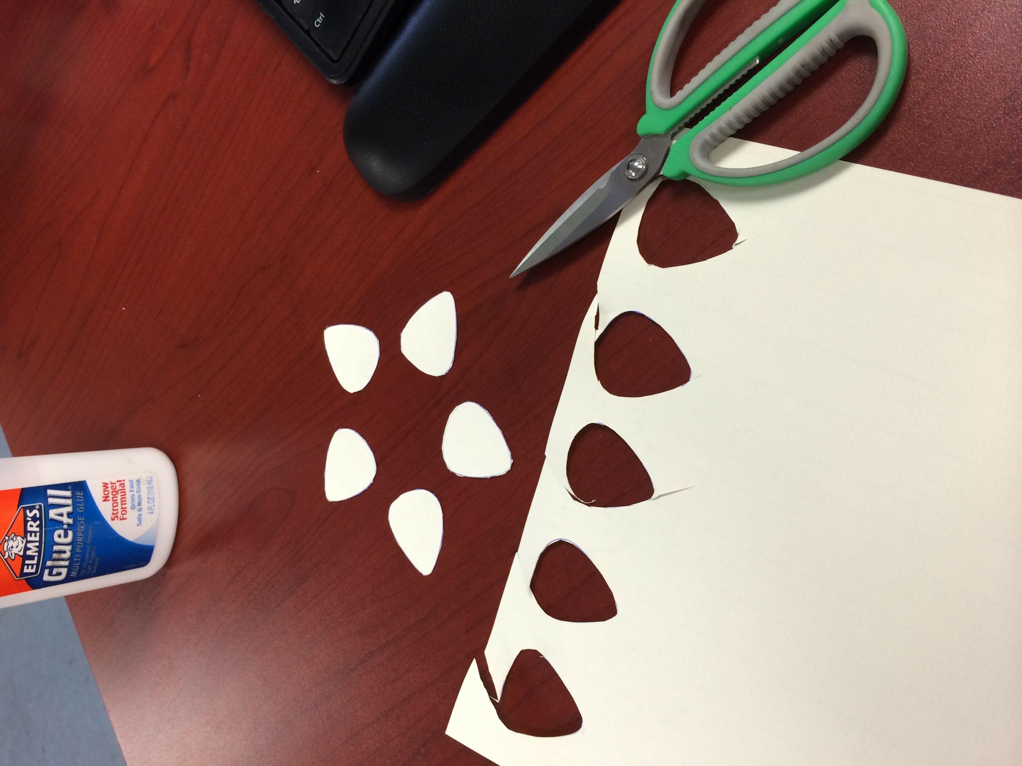 Guitar picks cut out of white paper and arranged in star shape on desk