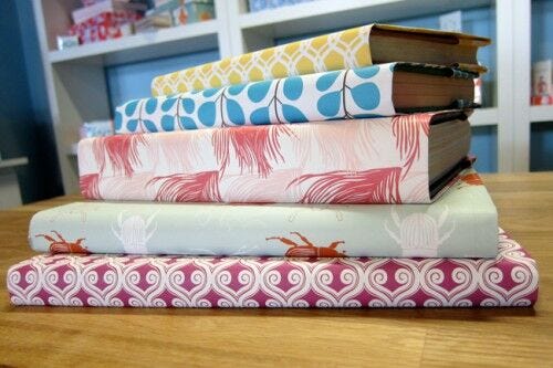stack of books with colorful patterned wrapping paper book covers