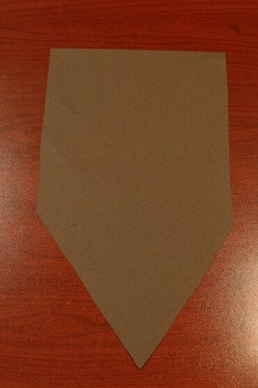 brown paper cut into elongated pentagon shape on desk