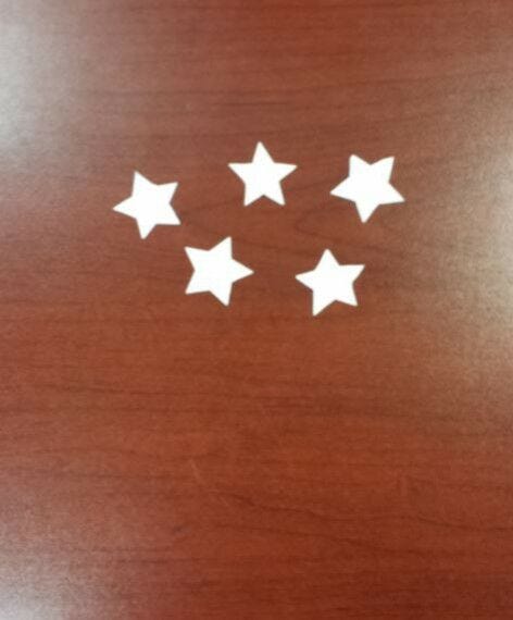 5 white paper stars cutout on wooden desk for labor day paper craft