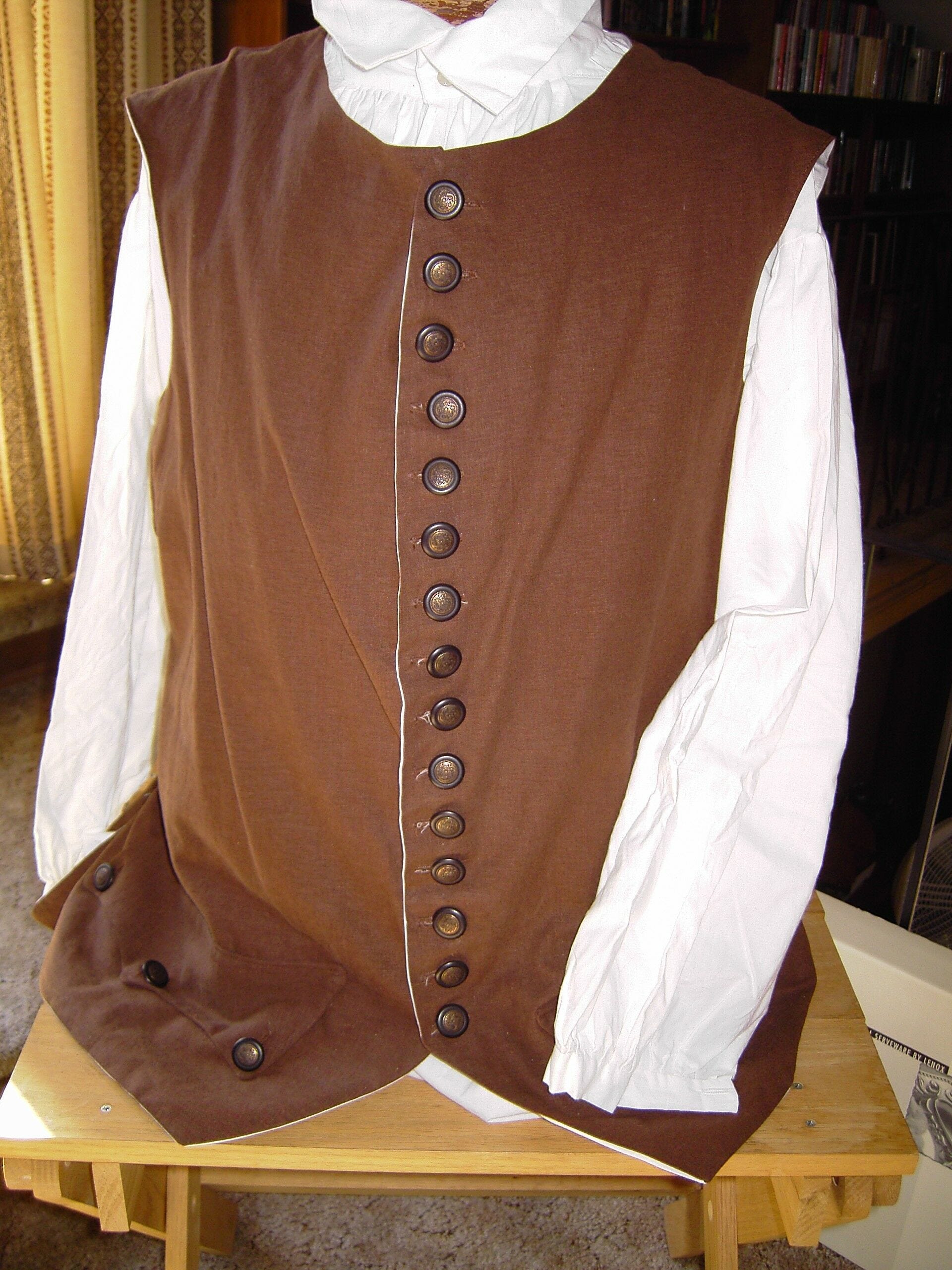 brown vest with row of brown buttons on mannequin with white long sleeve shirt