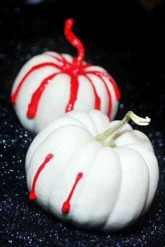 pumpkin carving alternatives: small white pumpkins with red fake blood oozing down sides