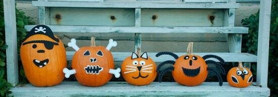 row of orange pumpkins with felt faces and decorations in descending height order