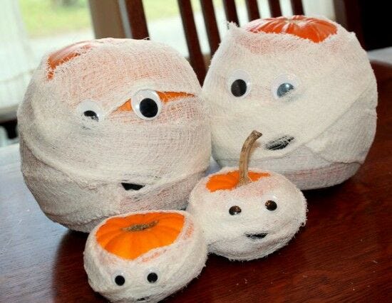 assorted orange pumpkins with googly eyes wrapped in white bandages