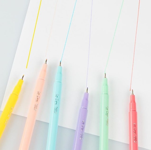 Red, green, purple, blue, pink, and yellow pastel Pens drawing lines on a white paper