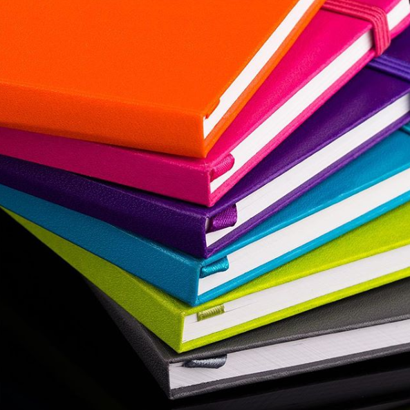 Stack of colorful journals on a dark black surface