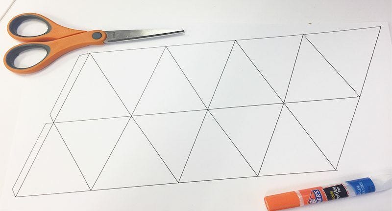 white paper with geometric triangle shapes, pair of scissors, and glue stick