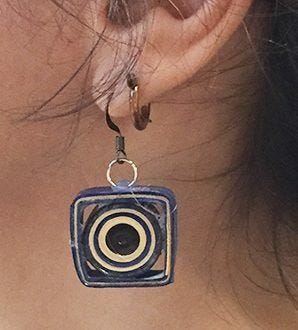 closeup of ear with circle inside square paper earring