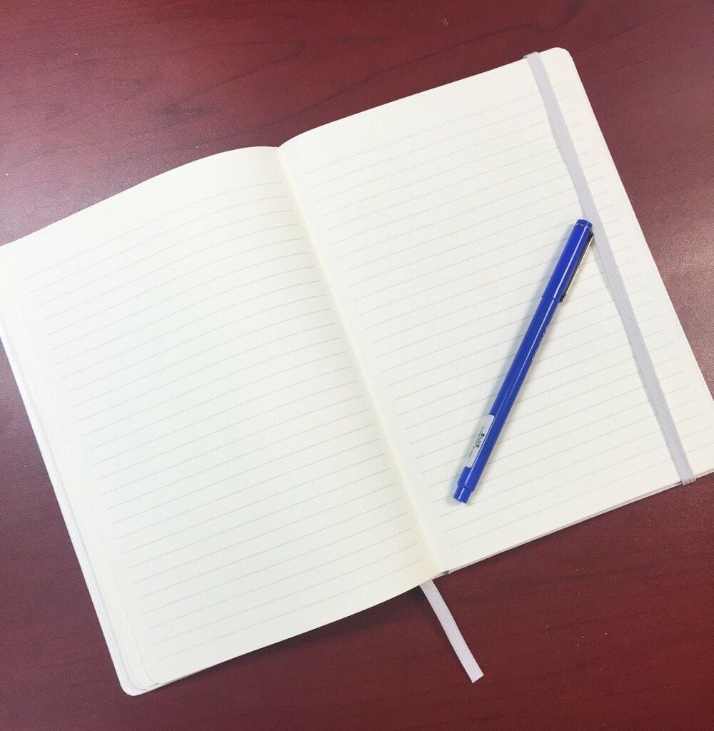 Open notebook on table, blue pen Notebook open, blue pen