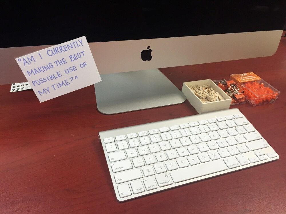 Desktop with Post-It note reading "Am I currently making the best possible use of my Time?" Post-It stuck to desktop, "Am I currently making the best possible use of my time?"