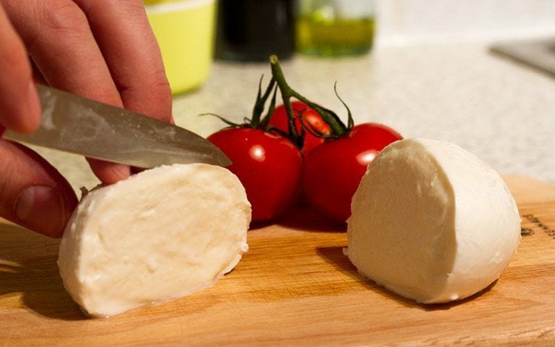 Tomato and cheese on cutting board Cheese and tomato on cutting board