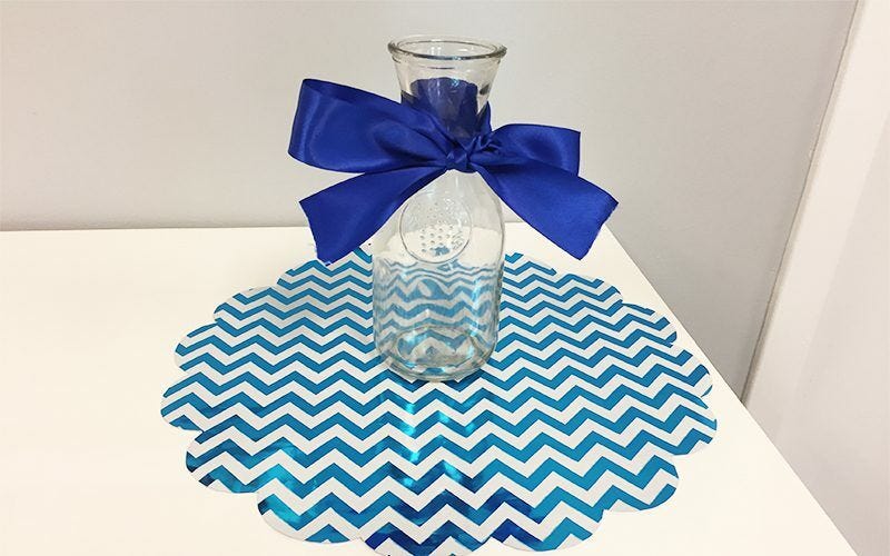 Glass container with blue ribbon placed on wrapping paper centerpiece