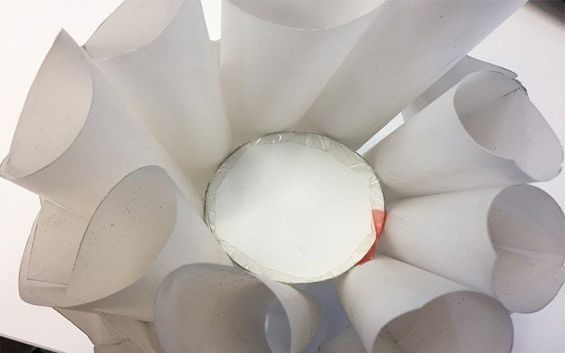 Lantern sections spread apart but held together by cylinder taped in the center Cylinder placed in open lantern and taped to hold it together and spread sections apart