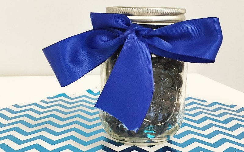 Mason jar filled with pebbles, blue ribbon, gift wrap centerpiece