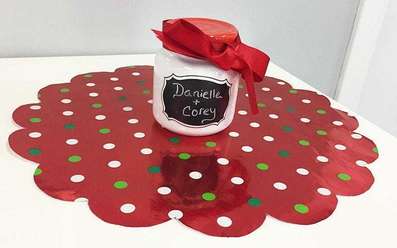 Jar with red ribbon, "Danielle + Corey" on wrapping paper centerpiece